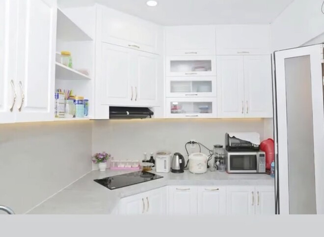 Khu bếp hiện đại với hệ tủ trắng, có đầy đủ thiết bị gia dụng thông minh, phục vụ nhu cầu nội trợ hàng ngày. Ảnh: FBNV