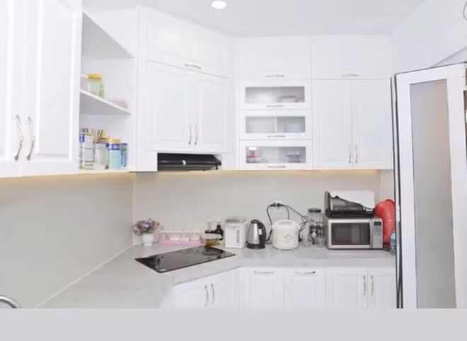 Khu bếp hiện đại với hệ tủ trắng, có đầy đủ thiết bị gia dụng thông minh, phục vụ nhu cầu nội trợ hàng ngày. Ảnh: FBNV