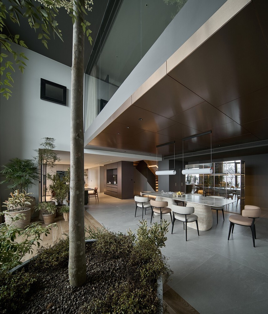 Sự kết nối theo chiều cao được nhấn mạnh qua các đường nét thẳng mạnh mẽ trong phòng khách, và những cây cao vươn lên trong khu vườn. Ảnh: Wuyhoang Studio