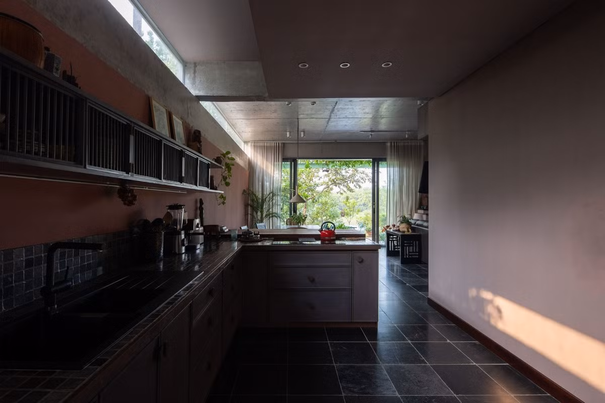 Bếp được đưa ra hướng bất lợi thành một trục kỹ thuật, thang và hành lang ở giữa kết nối các không gian. Ảnh: Chimnon studio