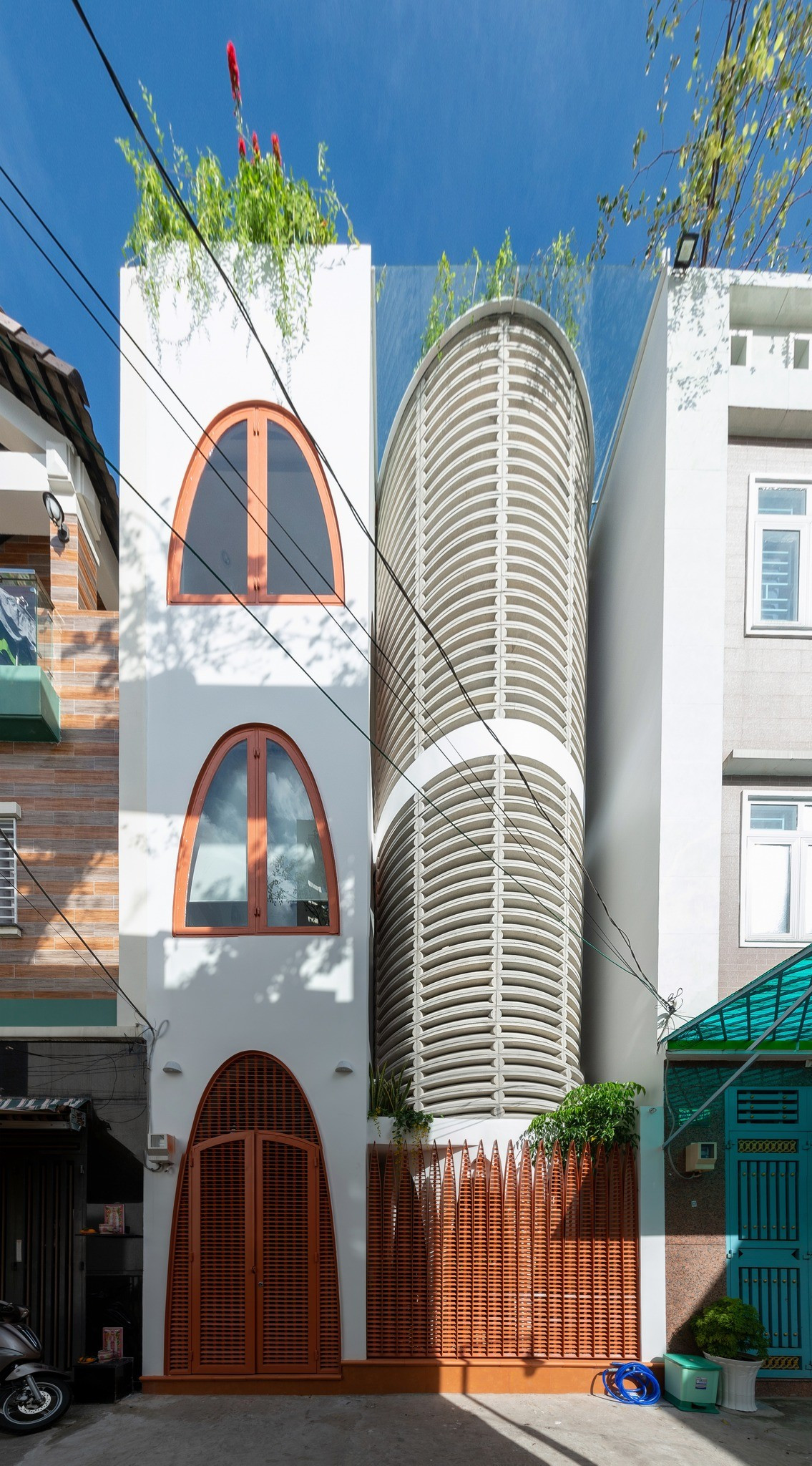 Ngôi nhà gây ấn tượng ngay từ mặt tiền với lõi thang xoắn vừa là điểm nhấn kiến trúc, vừa đóng vai trò “lá phổi” dẫn gió cho toàn bộ không gian sống. Ảnh: Lon ton studio