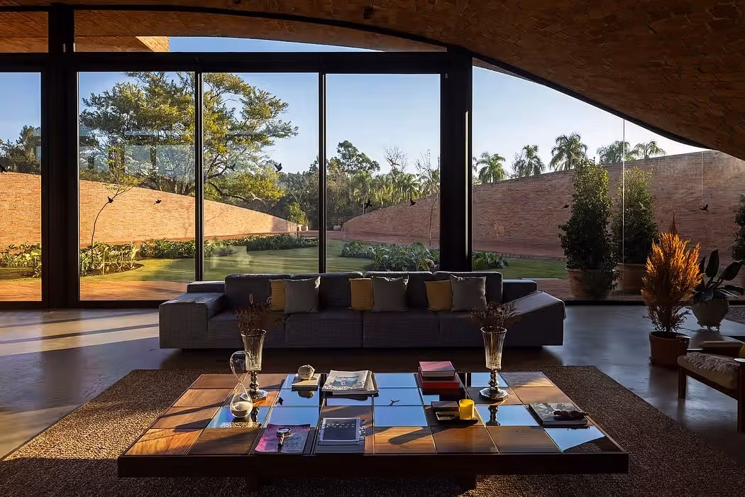 Ở tầng trệt, khu vực sinh hoạt chung và phòng khách được thiết kế liền mạch. Cách bài trí nội thất, gương nước, độ cong của mái nhà và độ dốc ánh sáng tạo nên bầu không khí riêng biệt mà không cần vách ngăn cứng nhắc. Ảnh: Homeadore