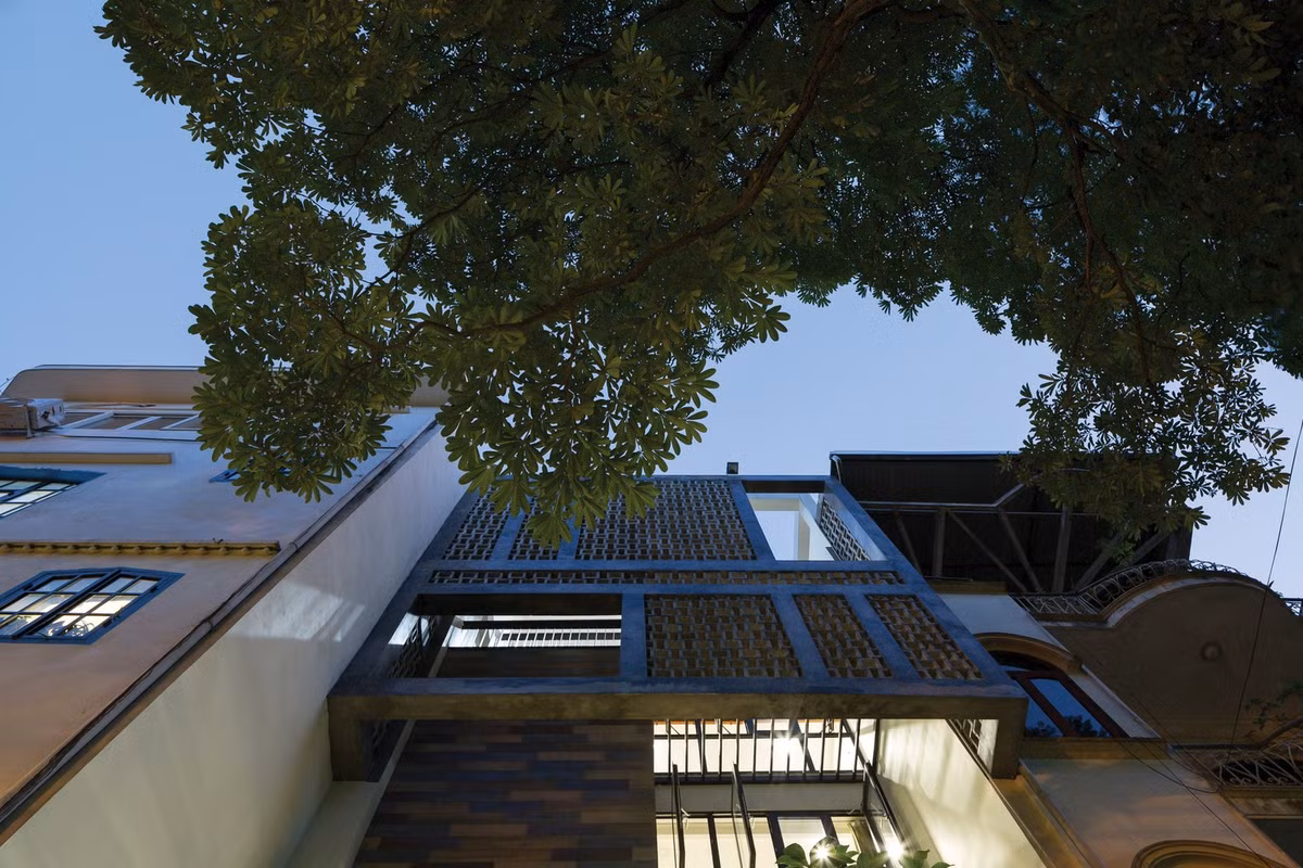 Tận dụng triệt để điều đó, kiến trúc sư bố trí mặt tiền bằng kính lớn và gạch thô rỗng, kết hợp cùng loggia lõm ngang và mảng xanh tầng hai để tạo điểm nhấn nhưng vẫn giữ được sự mộc mạc. Ảnh: Arcdaily