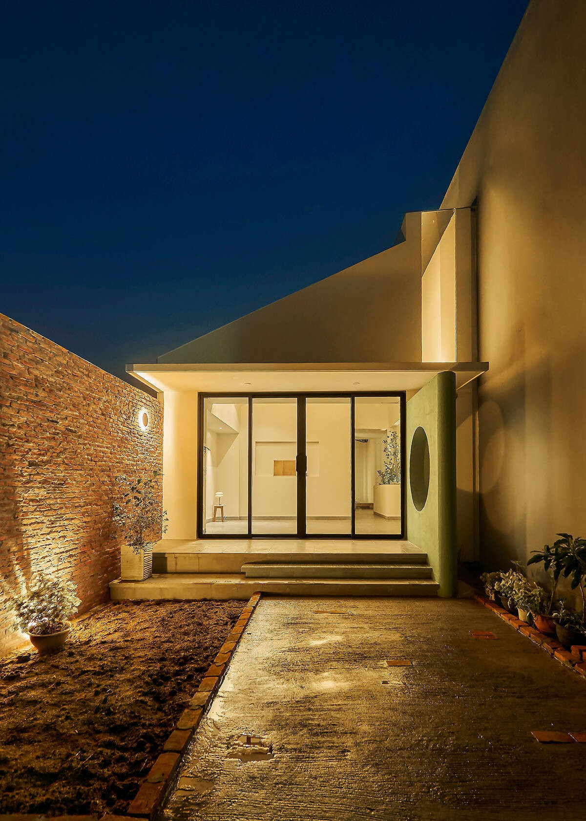 Đêm xuống, ánh sáng nội thất phản chiếu lên vách và mái kính, giúp ngôi nhà phát sáng nhẹ nhàng như một ngọn đèn trong khu phố. Ảnh: Nam Võ