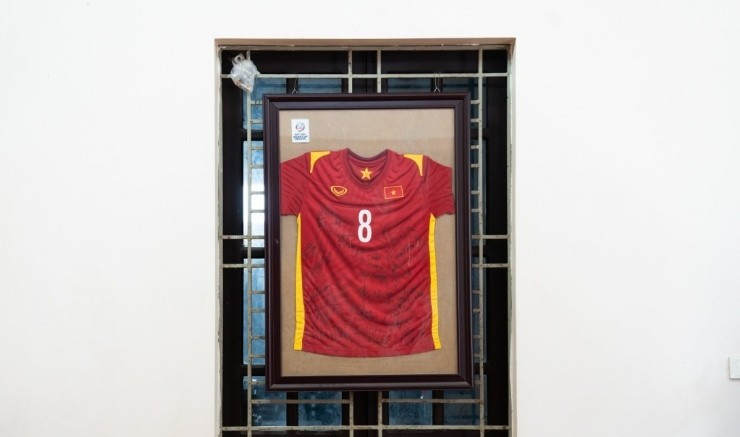 Chiếc áo đấu của đội tuyển U23 Việt Nam, in số 8 và có đầy đủ chữ ký của các cầu thủ, được đóng khung và treo trang trọng ở trung tâm phòng khách. Ảnh: Ngoisao