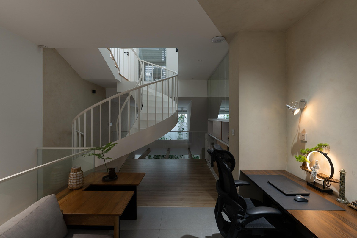 Tầng lửng là phòng khách và được kết nối bằng cầu thang cong, mang đến sự chuyển động mềm mại cho không gian. Ảnh: Quang Dam