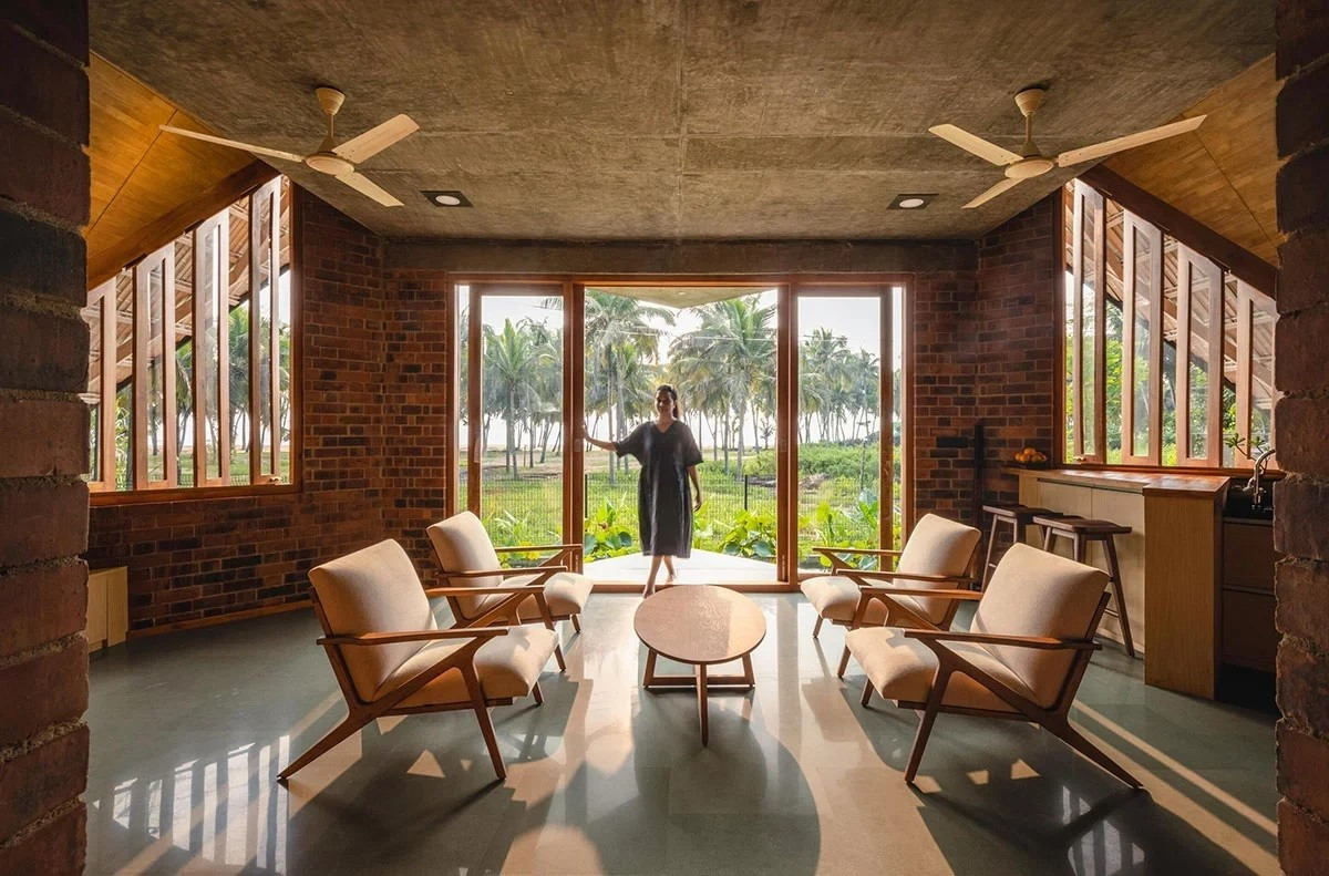 Phòng khách tối giản với cửa kính cao rộng, kết nối trực tiếp với không gian ngoài trời. Ảnh: Bhoomija