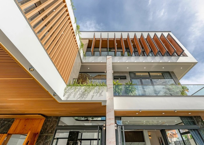 Các tấm cửa chớp di động và lam gỗ tại mặt đứng giúp che nắng nhưng vẫn đón được gió biển. Ảnh: HAVA Studio