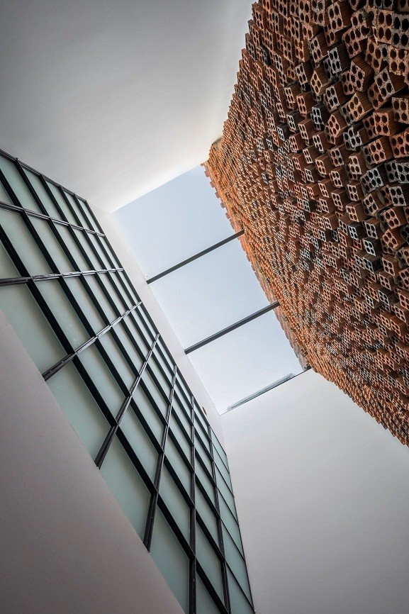 Ngoài những bức tường thở, kiến trúc sư còn thiết kế xen kẽ các khoảng giếng trời giúp chiếu sáng tới các khối phòng chức năng. Ảnh: Hiroyuki Oki