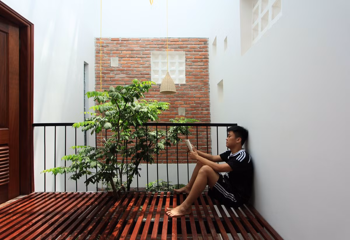 Tận dụng khoảng không của giếng trời sau nhà, kiến trúc sư thiết kế thêm ban công nhỏ ở tầng 2 để hưởng trọn ánh sáng từ giếng trời. Tại đây, gia chủ có thể thư giãn, uống tách trà hay đọc sách. Ảnh: My Anh Nguyen