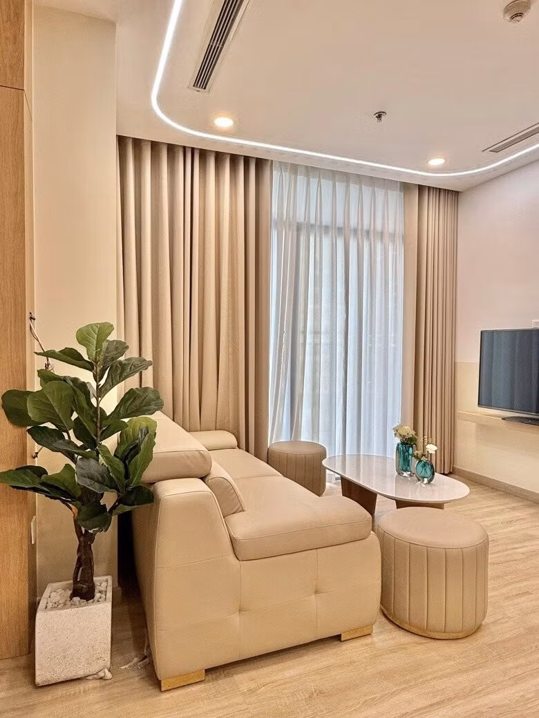 Phòng khách sáng sủa với sofa kem, bàn trà tròn và bình hoa xanh ngọc làm điểm nhấn. Ảnh: FB Nguyễn Văn Chung