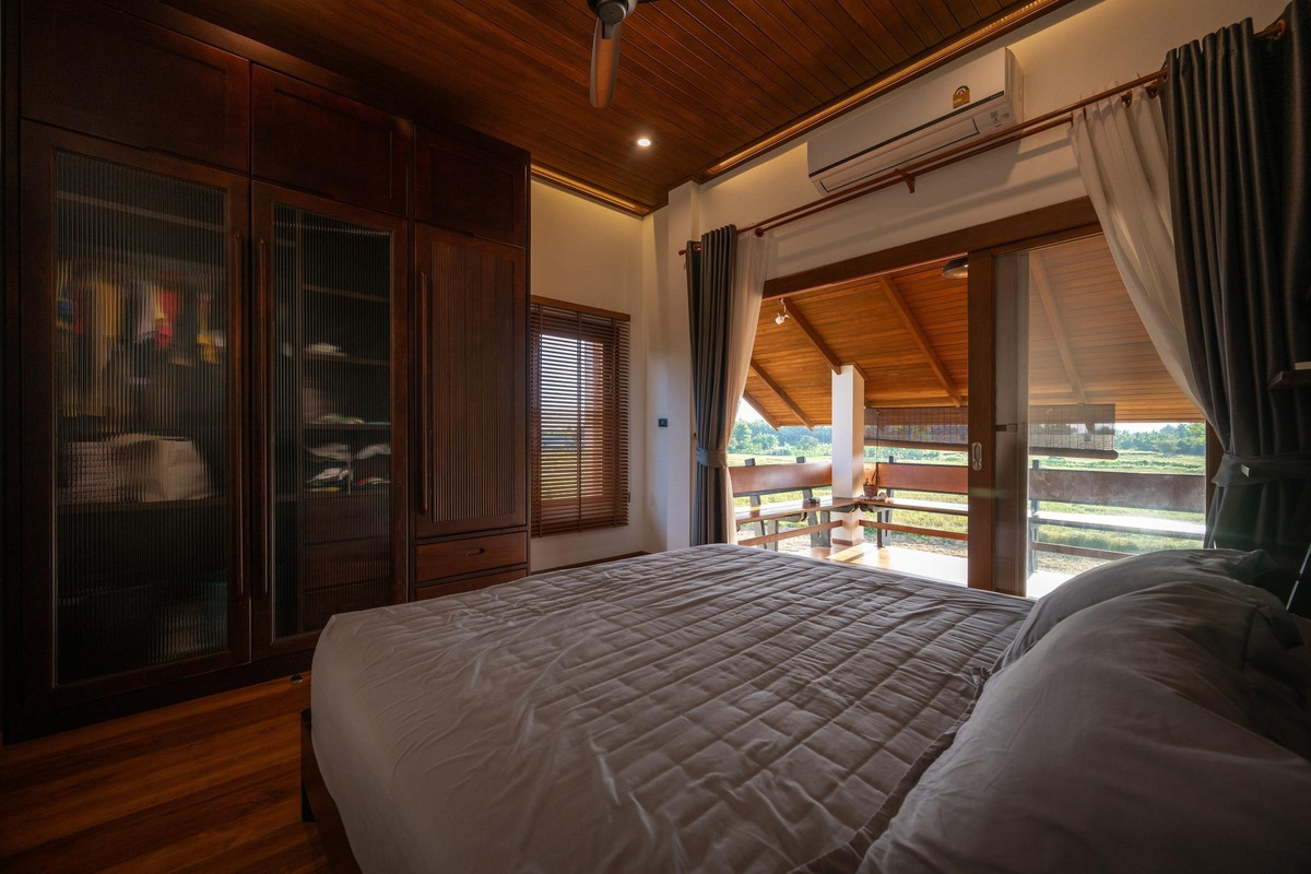 Phòng ngủ yên tĩnh có cửa kính mở ra ban công. Ảnh: Rungkit Charoenwat