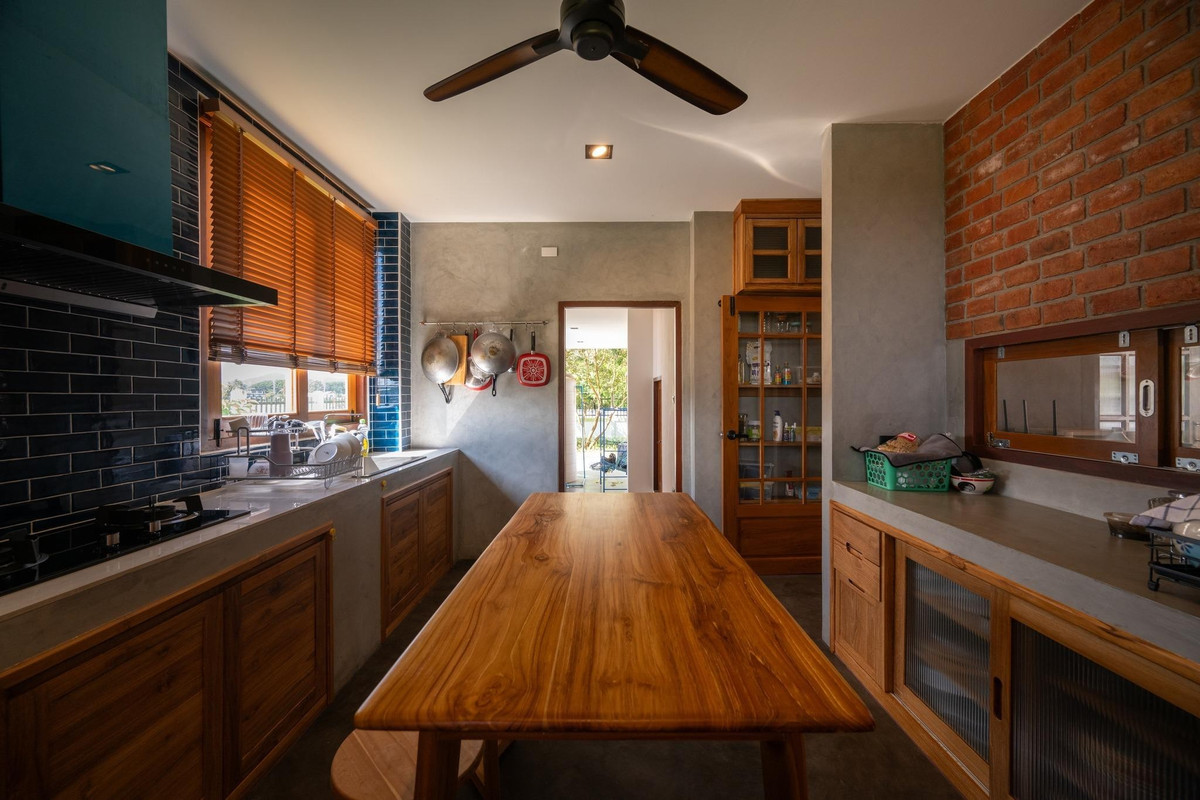 Khu bếp - ăn sử dụng gỗ tự nhiên, gạch và bê tông thô. Ảnh: Rungkit Charoenwat