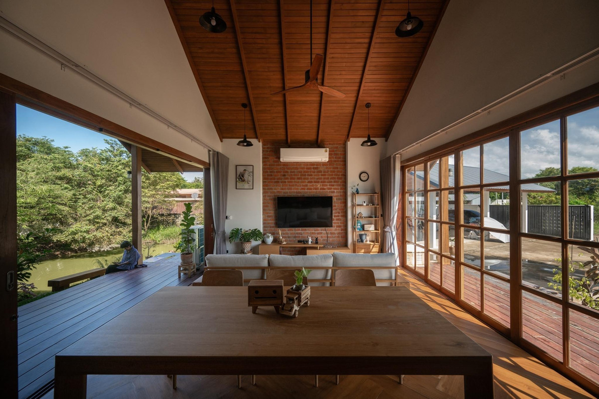 Cửa kính khung gỗ mở rộng toàn bộ không gian sinh hoạt chung. Ảnh: Rungkit Charoenwat