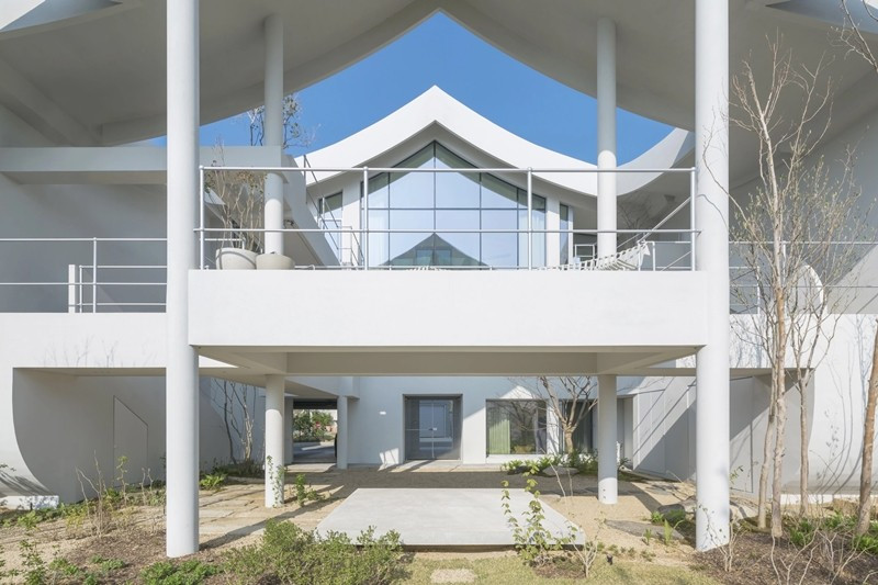 Lối vào nhà được bố trí dưới khoảng mái nhô rộng, dẫn tới khu vực sinh hoạt ở tầng một. Ảnh: Architizer