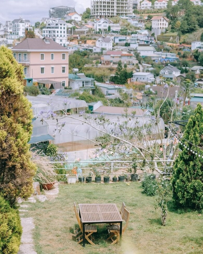 Bộ bàn ghế gỗ trắng đơn giản đặt giữa bãi cỏ xanh ở góc sân. Ảnh: Facebook