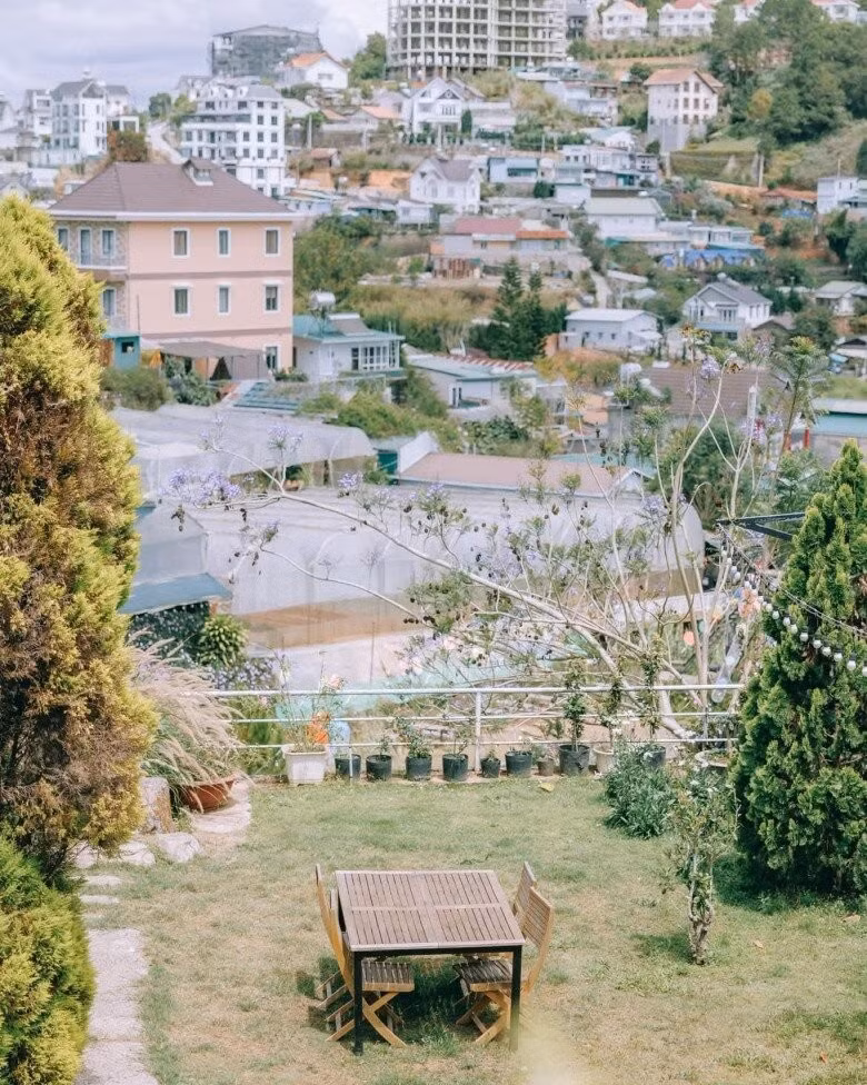 Bộ bàn ghế gỗ trắng đơn giản đặt giữa bãi cỏ xanh ở góc sân. Ảnh: Facebook