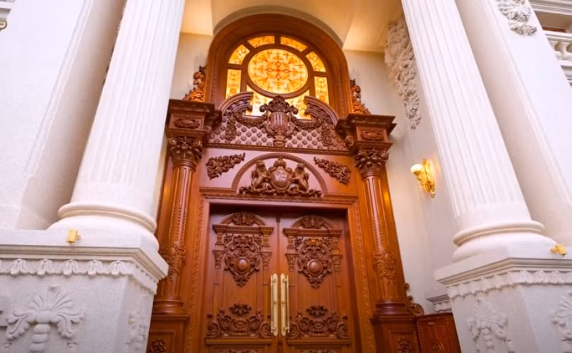 Cửa vào nhà bằng gỗ gõ đỏ, rộng 4,5 mét, cao 7,5 mét, thiết kế riêng biệt, mang tính cá nhân của gia chủ. Ảnh: chụp màn hình NhaTo