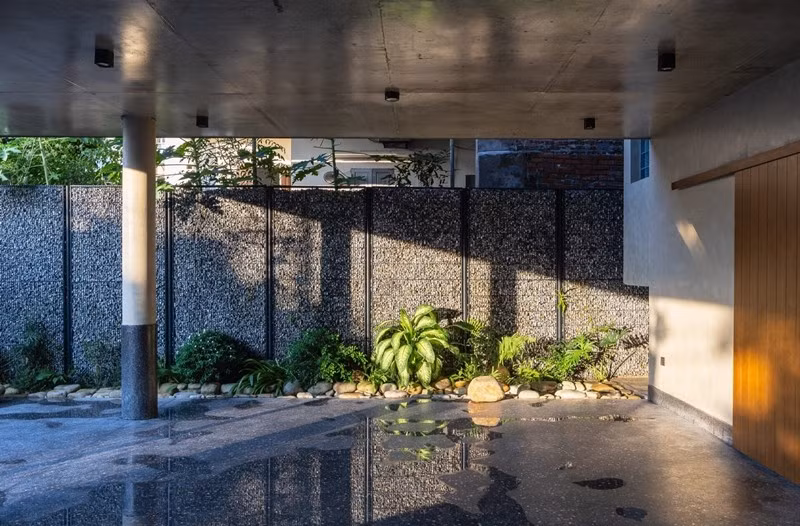 Bước qua cánh cổng là một không gian rộng mở, khoáng đãng, với khoảng sân đa chức năng, được bao bọc bởi hệ tường rọ đá kết hợp với những mảng xanh dịu và hồ nước trong veo. Ảnh: Trieu Chien