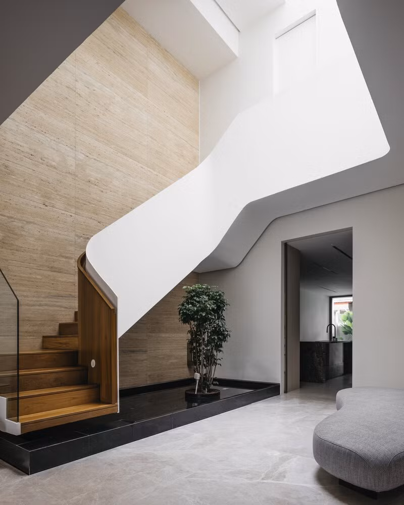 Ở trung tâm, một cầu thang lơ lửng uốn lượn, dường như không trọng lượng, gợi đến chuyển động của một dải ruy băng đang bay. Ảnh: Studio Periphery