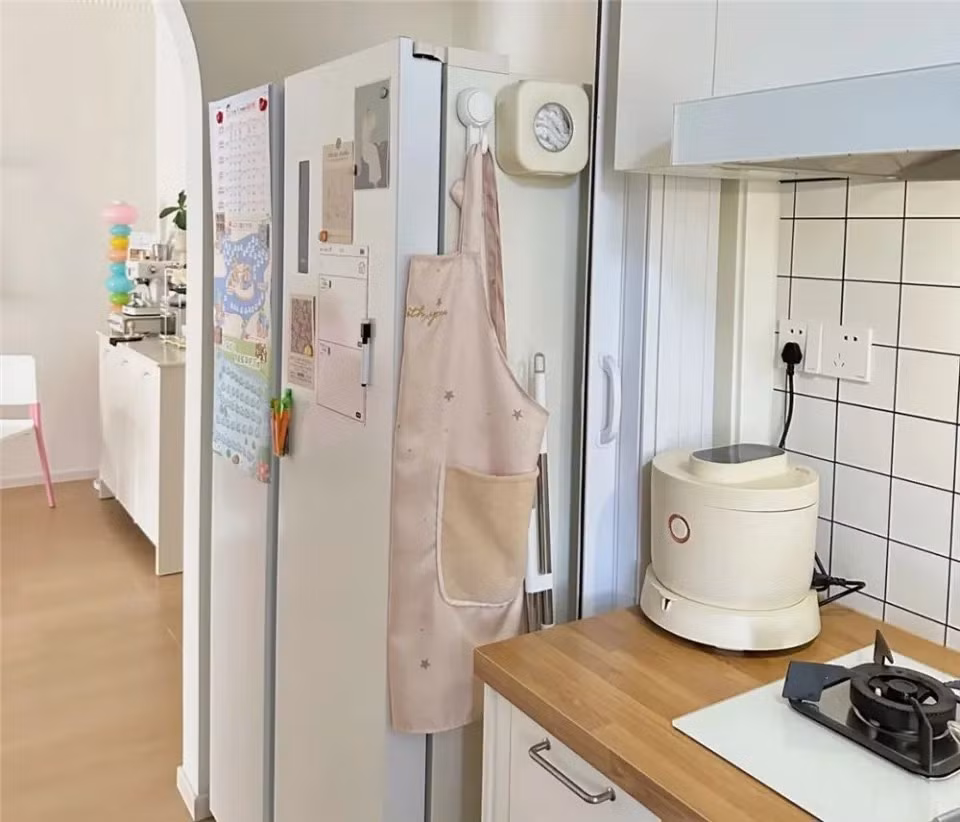 Khu bếp nhỏ xinh nhưng đầy đủ chức năng, được bố trí theo hình chữ U. Thay vì để tủ lạnh trong bếp chật, cô di chuyển tủ ra ngoài cửa bếp. Ảnh: QQ