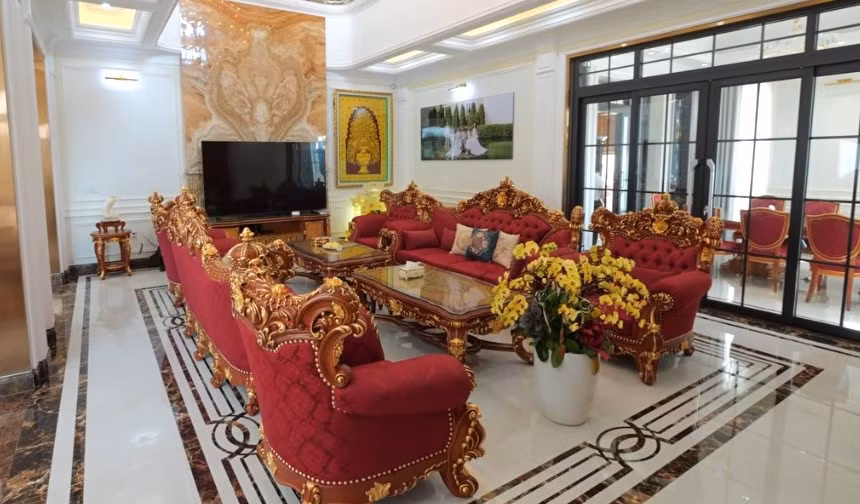 Phòng khách rộng rãi với bộ sofa lớn bằng gỗ gõ đỏ đồng nhất với cửa ra vào. Ảnh: Chụp màn hình