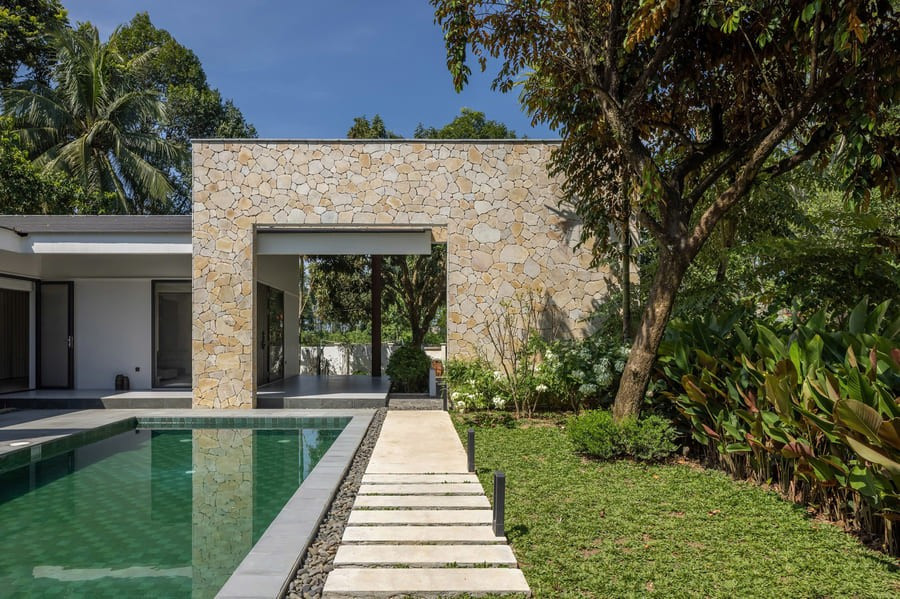 Lối vào dẫn đến gara và tiền sảnh, có mái đua sâu bảo vệ không gian sinh hoạt chung khỏi nắng mưa. Tiếp đến là khu vực hiên rộng bao quanh sân trong và hồ nước. Ảnh: Chimnon Studio