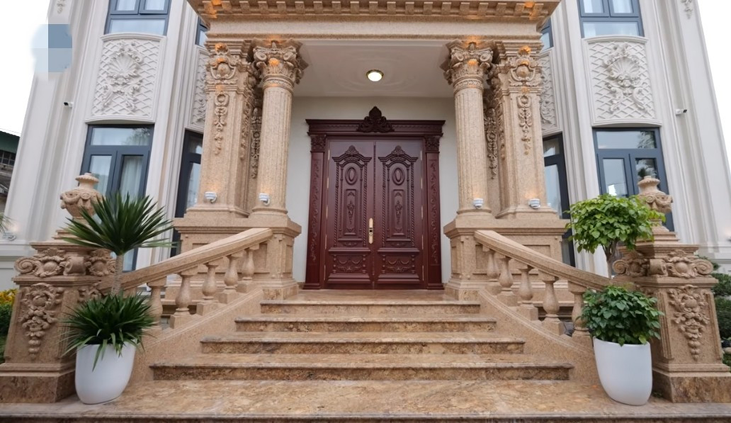 Lối vào sảnh chính cao thoáng, được ốp đá sang trọng, cửa bằng gỗ gõ đỏ. Ảnh chụp màn hình NhaF