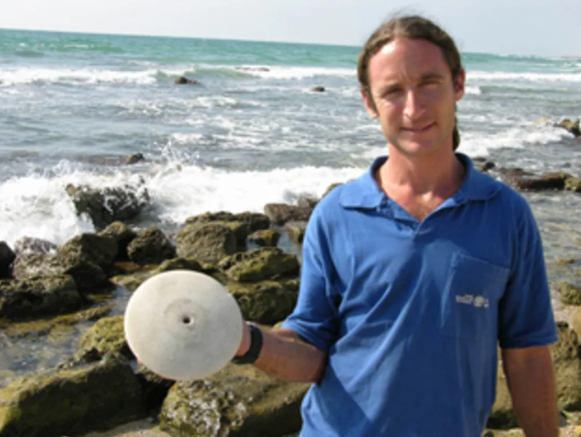 Đĩa đá cẩm thạch trắng lớn có đường kính 20 cm, phẳng ở một mặt và cong lồi ở mặt còn lại, có một lõm ở giữa đồng tâm. Đinh chì hoặc đồng được dùng để đính phần lỗ đồng tâm của đĩa vào thân tàu. Ảnh: @Cơ quan Cổ vật Israel.