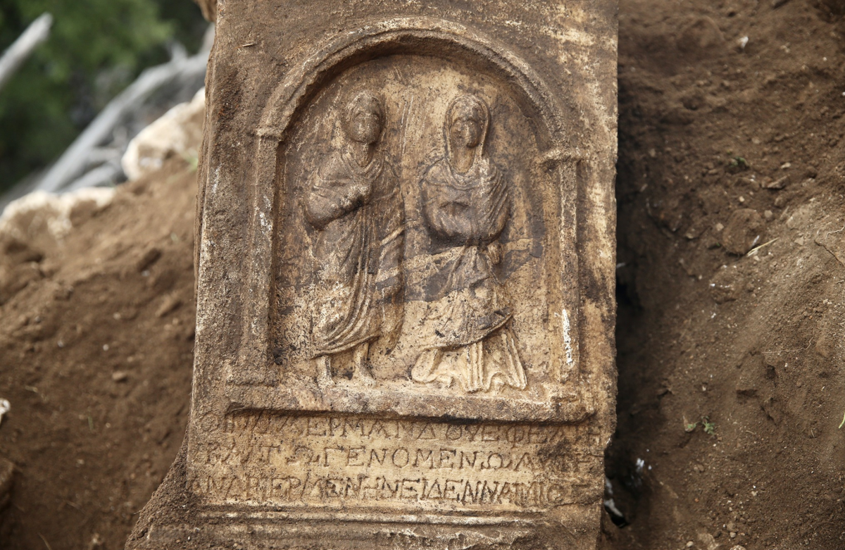 Mặt trước của tấm bia có hình một người đàn ông và một người phụ nữ đứng dưới mái vòm, có thể là một cặp vợ chồng, với dòng chữ Hy Lạp bên dưới. Ảnh: @Bảo tàng Fethiye.
