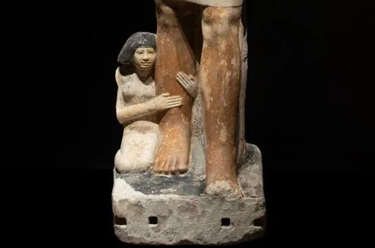 Bên cạnh ông, đang quỳ là vợ ông: vốn nhỏ bé về tỷ lệ, nhưng không kém phần quan trọng. Với cử chỉ và tư thế của mình, bà tựa vào chân chồng như một chỗ dựa, bà mặc một chiếc váy ôm đơn giản, được nhấn nhá bởi một chiếc cổ áo lớn. Ảnh: @Hội Đồng Cổ Vật Tối Cao Ai Cập.