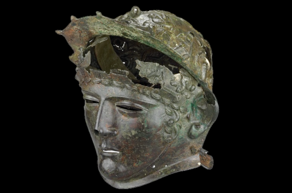 Mũ giáp gồm hai phần chính, một mũ trùm đầu được trang trí bằng cảnh chiến binh và mặt nạ được làm theo hình dạng khuôn mặt của một thanh niên. Ảnh: @Hội đồng quản trị Bảo tàng Anh.