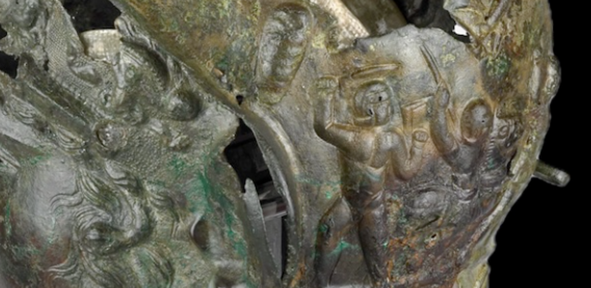 Mặc dù ít hơn về số lượng, kỵ binh dường như chiếm ưu thế, vì hai bộ binh đã nằm chết. Chiếc mũ sắt cũng có hai họa tiết hình lá cọ tượng trưng cho chiến thắng, một chiếc khiên biểu thị áo giáp của kẻ thù bị thu giữ, và những chiếc giáo. Các lỗ ở phía sau gáy cho thấy rằng các dải sọc từng được gắn vào mũ sắt. Ảnh: @Hội đồng quản trị Bảo tàng Anh.