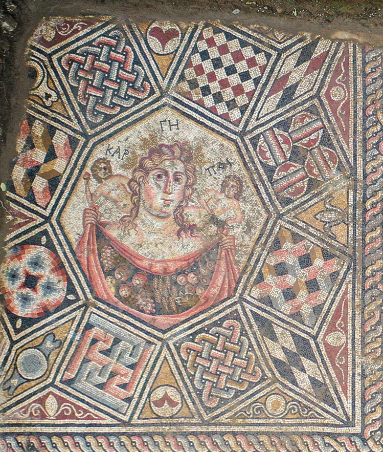 Đầu tiên là bố cục một hình ảnh người phụ nữ với một giỏ nông sản (gồm lựu, nho, lúa mì) cùng hai hình trẻ nhỏ nằm nghiêng phía trên mỗi vai. Ảnh: @Bảo tàng İznik.