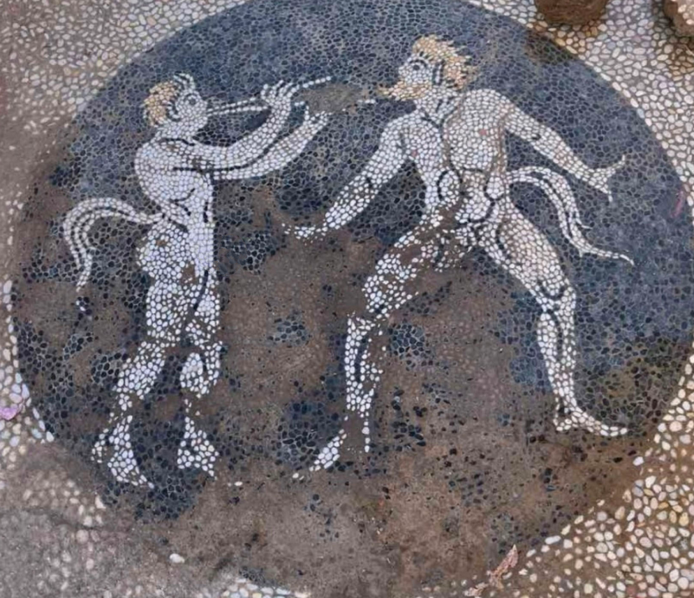 Đó là một bức sàn khảm sỏi với hình ảnh huy chương tròn kỳ lạ làm từ các loại sỏi đen và trắng. Trung tâm của bức huy chương khảm sỏi này là hai vị thần rừng Satyr có trong thần thoại Hy Lạp cổ đại. Ảnh: @Bộ Văn hóa Hy Lạp.