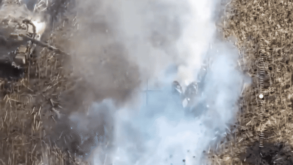 Một người chạy băng qua mũi xe tăng Ukraine, hướng đến vạt rừng gần đó, hai người khác nấp sau thiết giáp đang bốc khói.