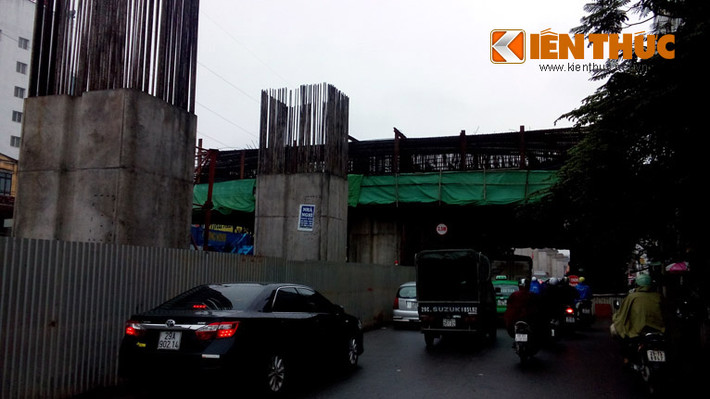 Sắt thép, vật liệu xây dựng phía trên công trình thuộc khu vực thi công ngã tư Hoàng Cầu - Xã Đàn, quận Đống Đa, Hà Nội. Ngay phía dưới là người dân và đủ loại phương tiện giao thông đang di chuyển.