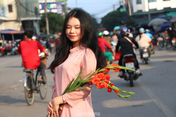 Ôm cành hoa lay ơn, cành đào hay tầm xuân tạo dáng.