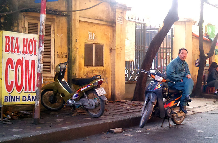 Trời rét nên khách hàng đi xe ôm cũng vắng hẳn, hầu hết đều chọn taxi. Trong ảnh: một bác lái xe ôm mặc cả áo dày chống rét để chờ khách nhưng vẫn không có ai hỏi han.