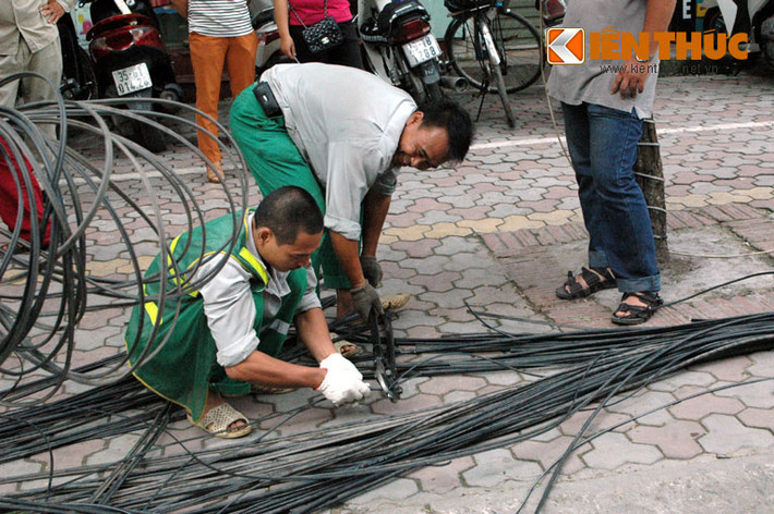 Các công nhân tiến hành cắt những dây cáp thông tin rơi dưới mặt đất.