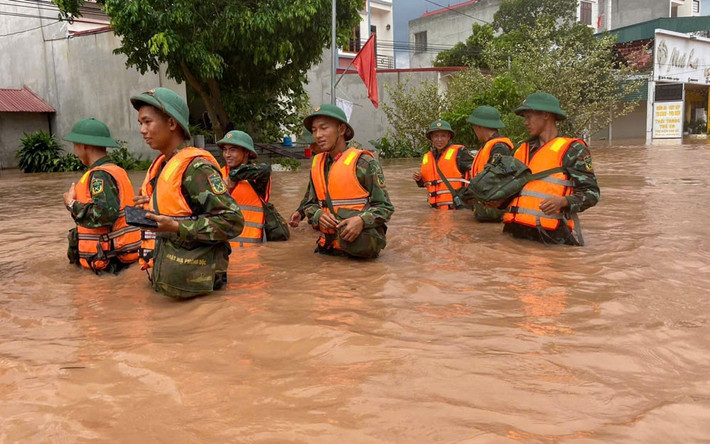 Cán bộ, chiến sĩ lực lượng vũ trang vượt qua đoạn đường ngập sâu trên QL 31 đến giúp chính quyền, nhân dân xã Phì Điền (Lục Ngạn) khắc phục hậu quả mưa bão.