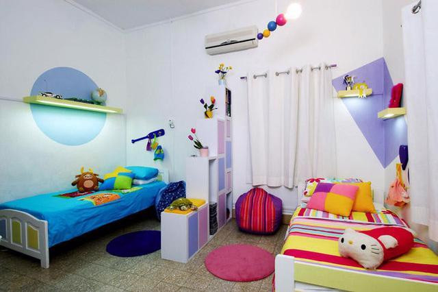 2 giường ngủ được ngăn bằng 1 kệ chung dùng để cất trữ đồ chơi. Mỗi khu vực ngủ của trẻ đều được trang trí theo phong cách riêng với màu sắc vui nhộn và những món đồ yêu thích của mỗi bé