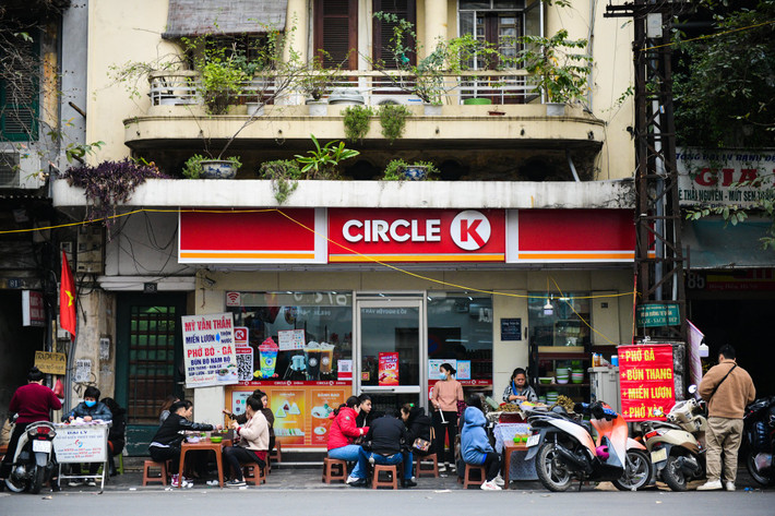 Phần vỉa hè ít ỏi phía trước một cửa hàng tiện lợi cũng được một gánh bún, phở bày kín bàn ghế.