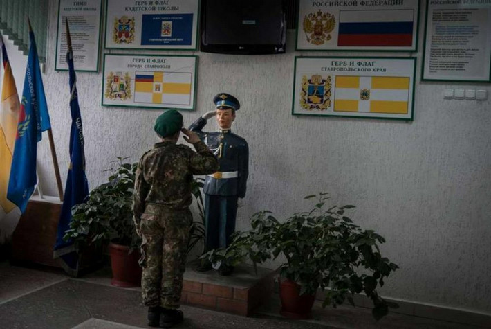 Cậu bé thực hiện nghi thức chào trong quân đội với đồng đội.