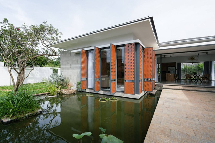 Khối phòng khách nằm bên trái lối vào được thiết kê như nổi trên một mặt nước bể cảnh. Điểm nhấn là những cánh cửa lớp ngoài đục lỗ có màu sắc nổi bật.