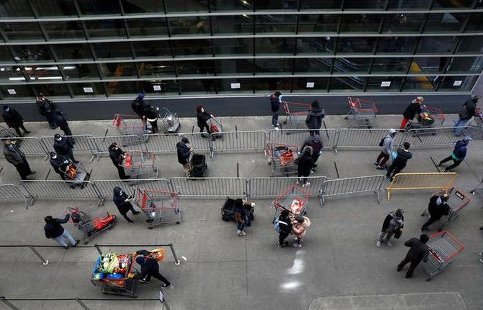 Người tiêu dùng tuân thủ khoảng cách xã hội trong lúc chờ trước cửa hàng ở Manhattan, New York. Ảnh: Reuters.