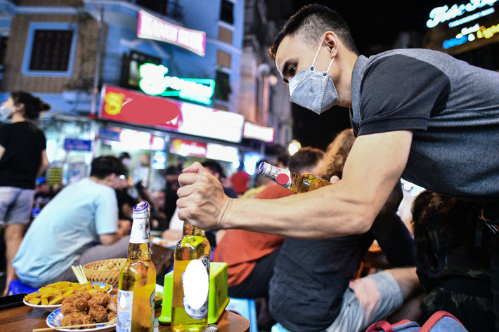 Chủ một quán bia liên tục mở đồ uống cho khách. "Quán tôi nằm ngay ở vị trí ngã tư đắc địa nên đông đúc, khách lui tới liên tục nên từ khoảng 21h lúc nào bàn cũng kín chỗ", anh chia sẻ.