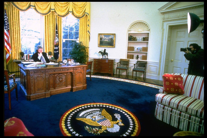 br/> Trước đó, cựu Tổng thống Bill Clinton cũng bài trí Phòng Bầu dục gần giống với người kế nhiệm. Điểm khác biệt nằm ở chỗ tấm thảm lớn trong phòng có sắc xanh lam nổi bật. Chính giữa thảm là họa tiết in hình quốc huy, đại diện cho sức mạnh của nước Mỹ: đại bàng đầu trắng dang cánh, một chân cầm cành olive, một chân ôm bó mũi tên.