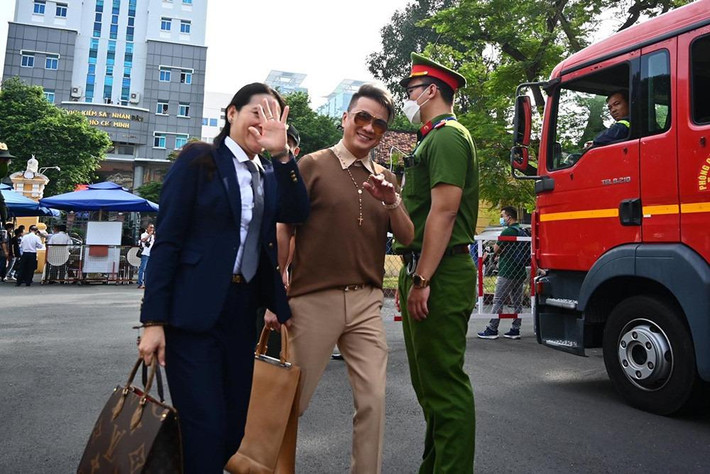 am ca sĩ diện trang phục hàng hiệu, tươi cười vẫy chào ống kính phóng viên.