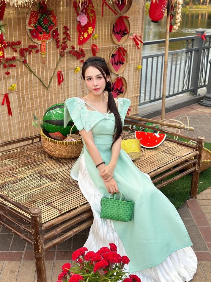 Á hậu Ngọc Hằng diện áo dài cách tân tông màu xanh pastel, phối cùng túi cói màu xanh độc đáo.